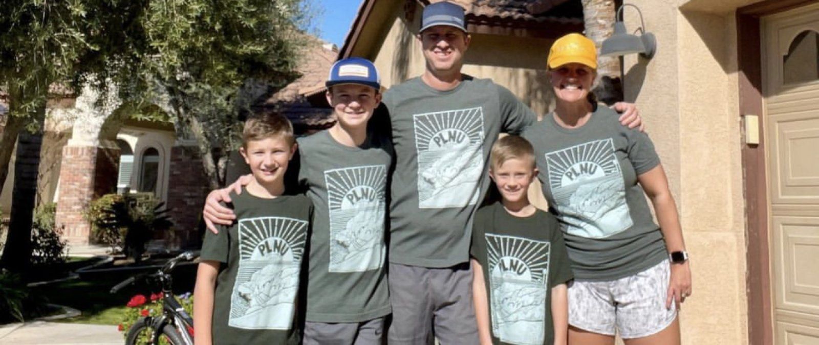 Family in green PLNU T shirts out side
