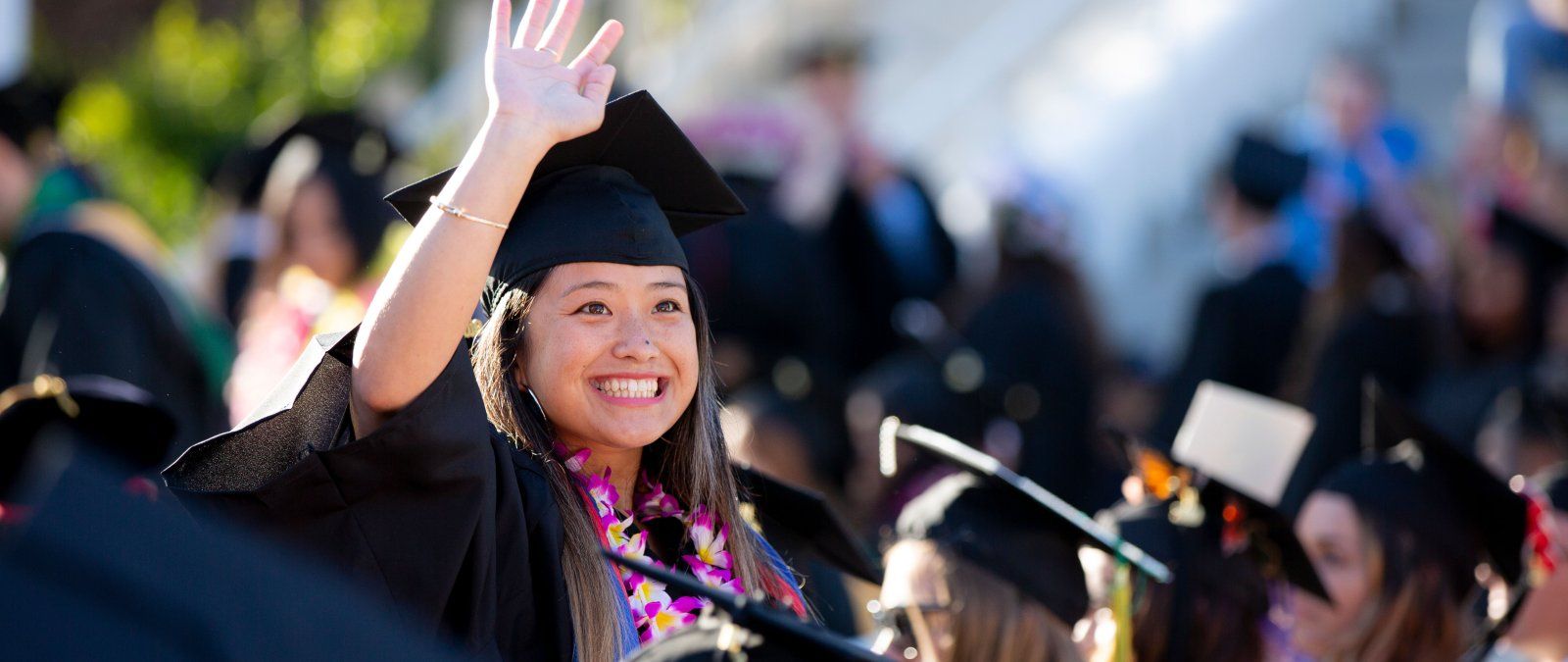 student in a cap and gown waving 