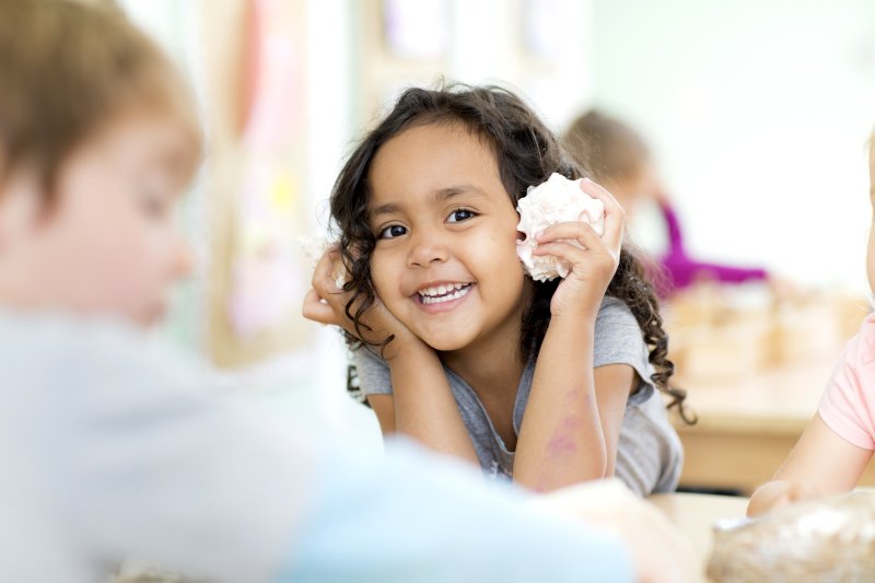 little kid with a shell to their ear