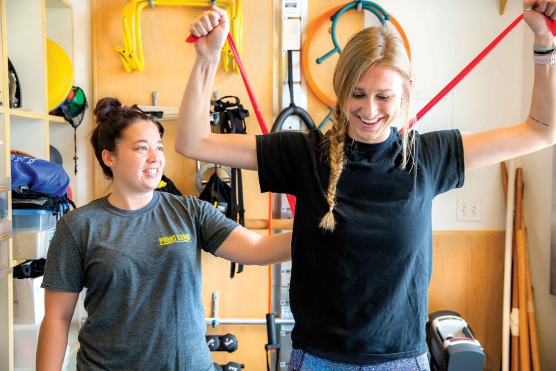 athletic trainer coaching an athlete with resistance bands