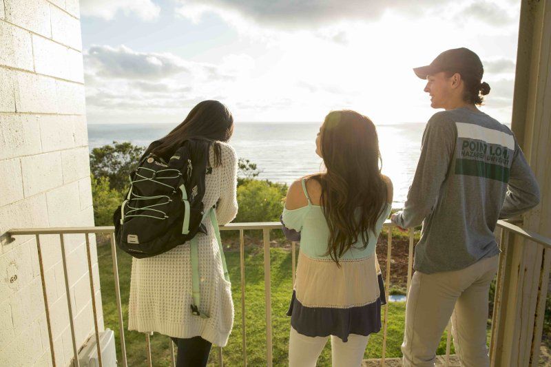 Three PLNU students watch the sunset over the ocean