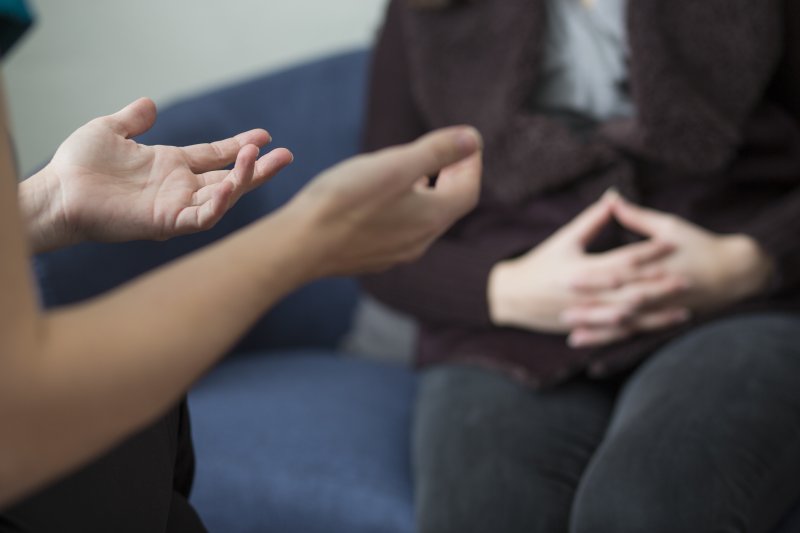 Counselor speaks with their patient on a couch. 