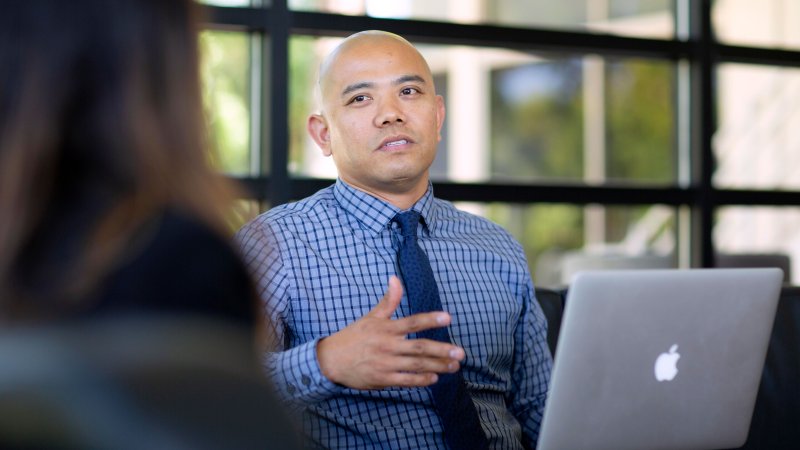 Man with a laptop speaks with a woman.