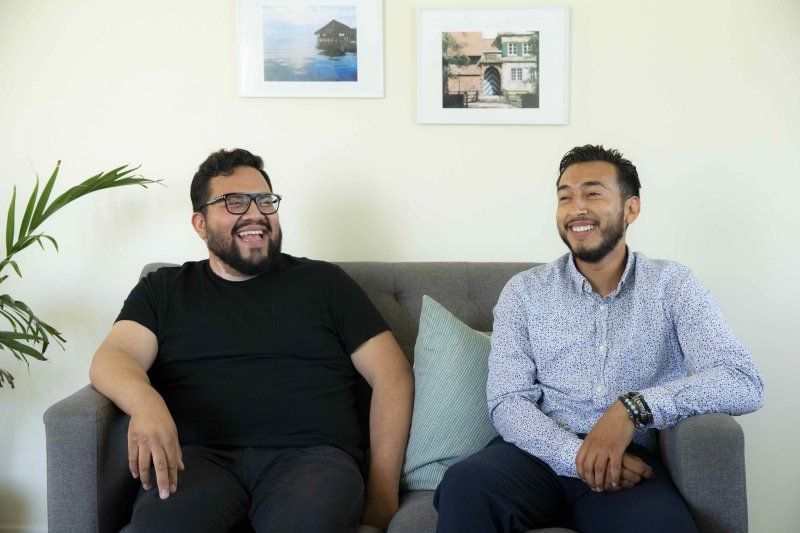 two men sitting on a couch laughing