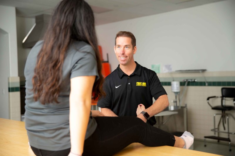 Man works on a patients ankle in therapy