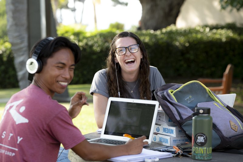 a woman and man studying while laughing at the camera