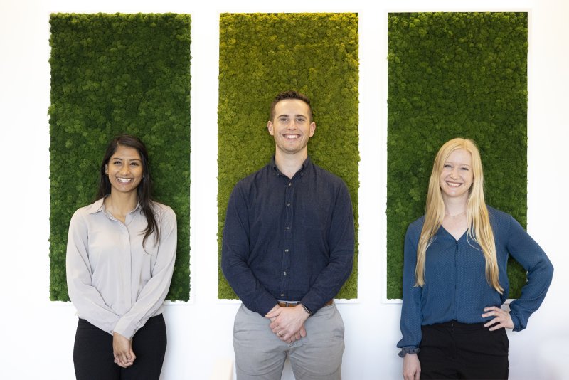 Three adult degree completion students are standing next to each other, smiling.