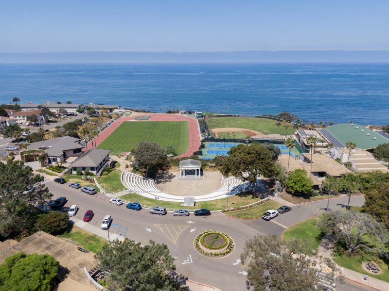 A drone image of the southern-central part of PLNU's campus, including the Greek Amphitheatre, soccer and baseball fields, tennis courts, and vast Pacific Ocean.