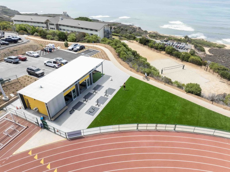 Aerial view of the Lawrence Ryan Fitness Pavilion, athletic track, lawn, and surrounding coastal campus.
