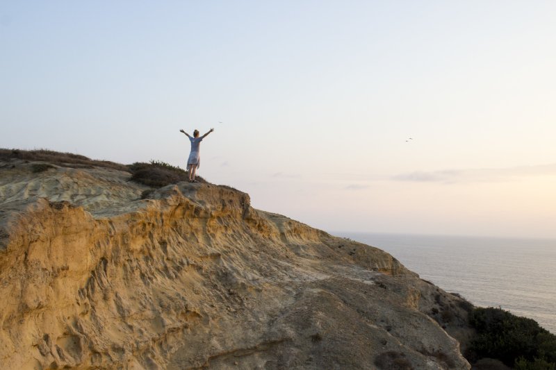 A woman throws hands up in joy at Torrey Pines