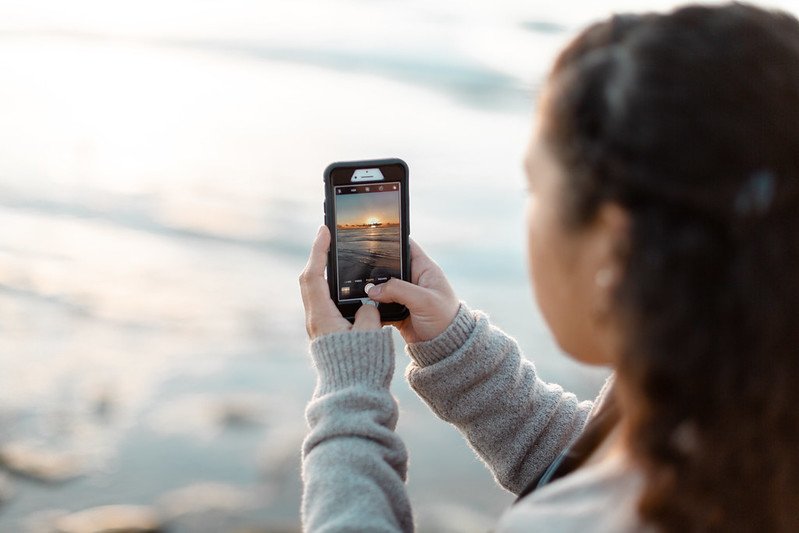 Student with phone takes photo of sunset