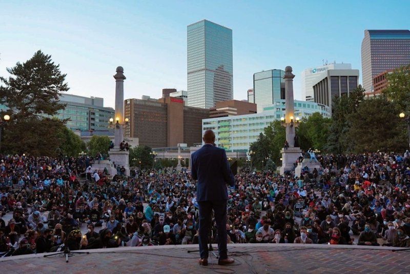A speaker stands in front of a large crowd at a Black Lives Matter Protest
