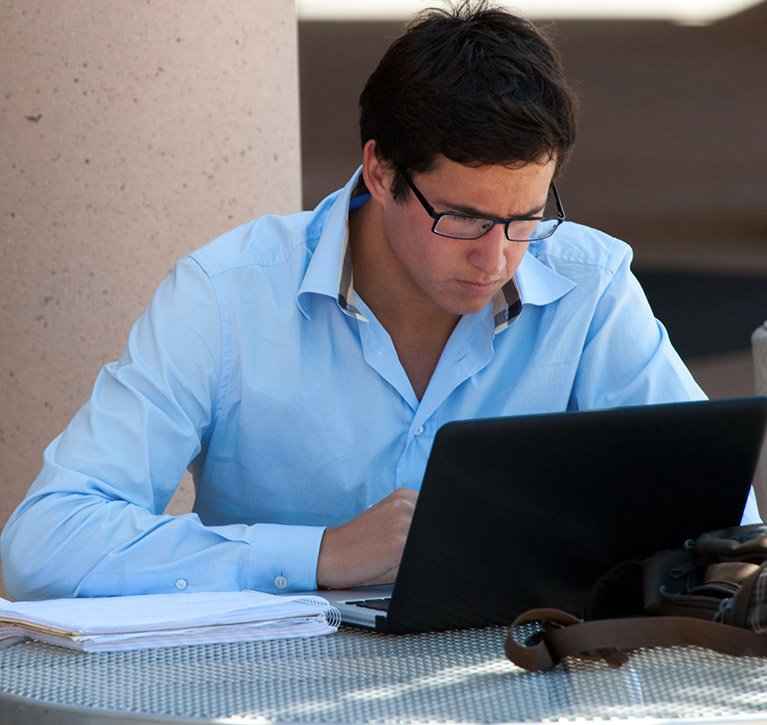 A student works diligently on his laptop