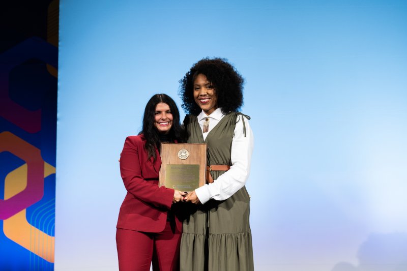 PLNU iWell program director Jessica Matthews stands on the ACLM stage to receive an award.