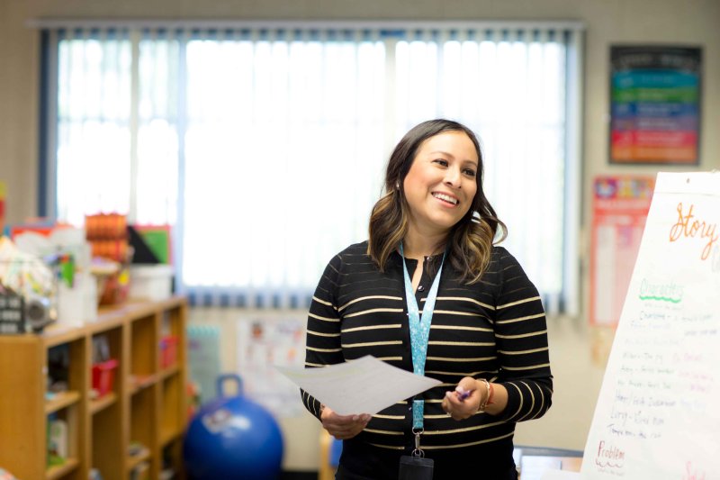 A school teacher smiles while in the classroom