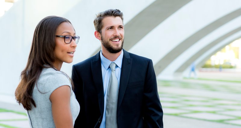 Male and female student look off camera as they meet under structure