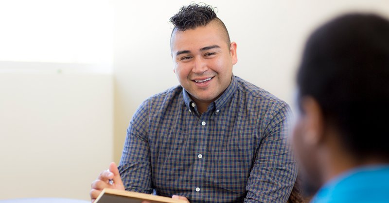 A counselor looks and smiles at a man he is talking with