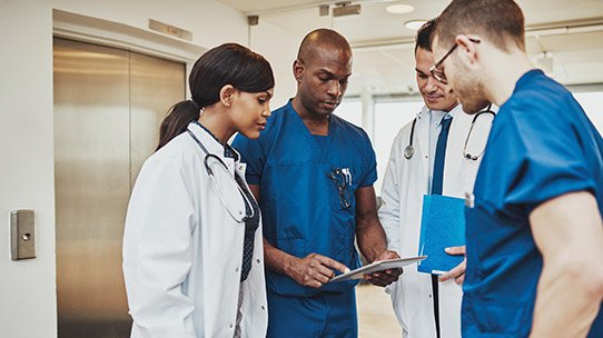 A group of nurses and doctors talk about a patient's charts.