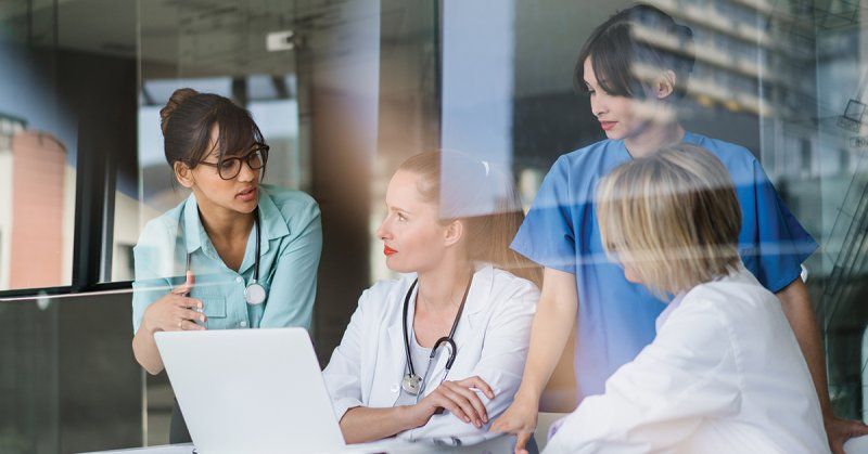 A group of nurses sit and plan the day together.