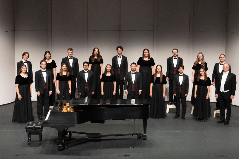 Male and female singers lined up on stage, wearing concert black dresses and tuxedos