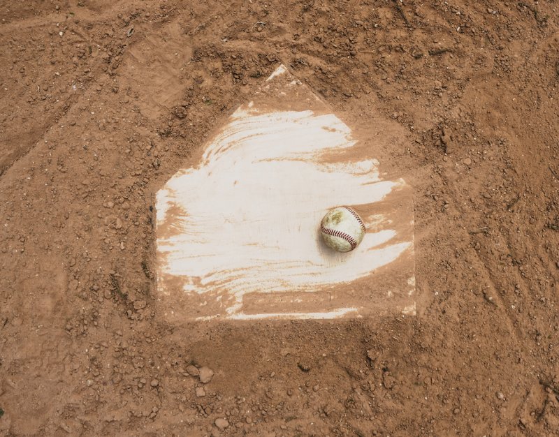Homeplate of a baseball field with a baseball on it, surrounded by dirt.
