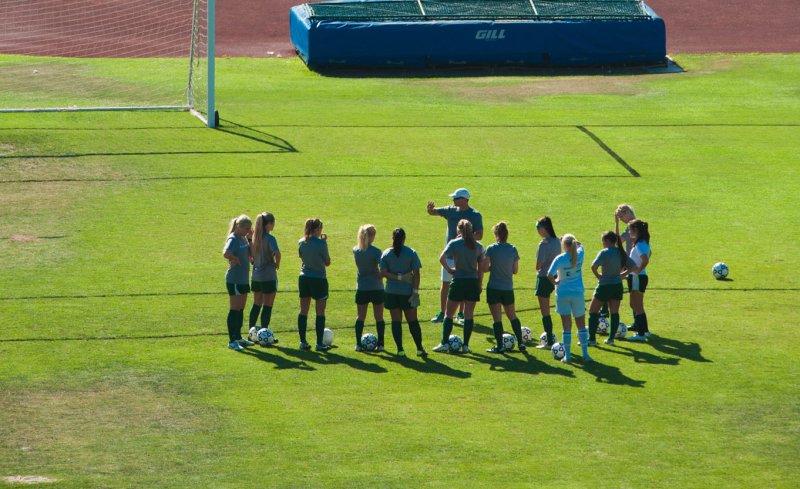 Soccer coach teaching student athletes on field