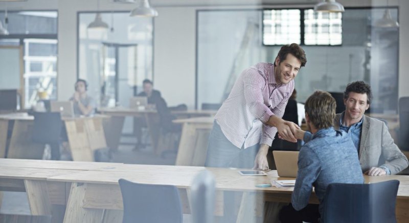 Man shakes hand of another person at a business meeting.