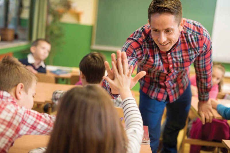 A male teacher hi-fives a student