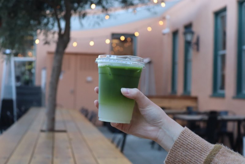 A girl holds up tea at Moniker coffee in San Diego