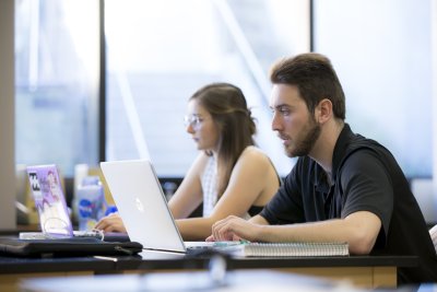 PLNU students typing notes on laptop during class lecture.