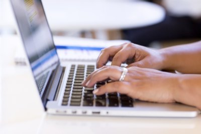 Individual typing on laptop.