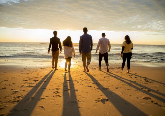 People walk towards the ocean and sunset
