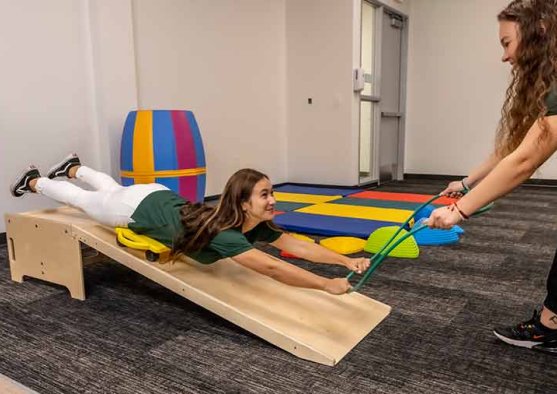 An MSOT student pulls another student down a slide in an classroom training