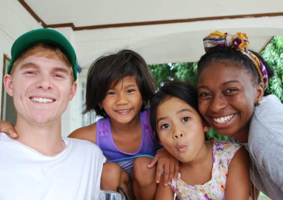Mitchell and Jordan smile at the camera with Filipino children making funny faces.