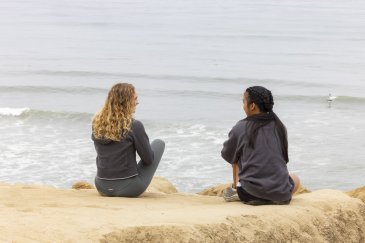 Two students sitting and talking on the Sunset Cliffs.