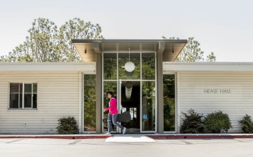 A student walks out the door of Nease Hall on her way to class.