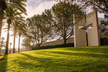 brown chapel surrounded by trees and palm trees