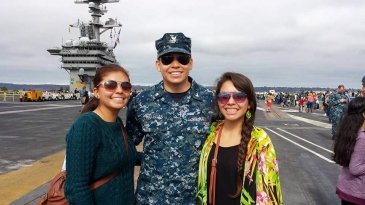 3 people posing a photo. there is a man in the middle wearing a military uniform 