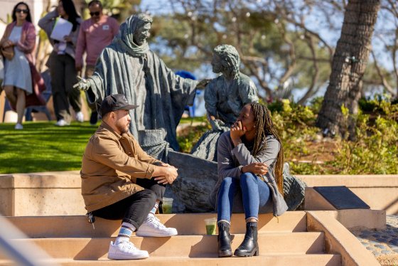 students talking in front of a statue